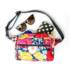 a colorful flowered purse with sunglasses and polka dots on the front, sitting on a white surface