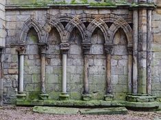 an old building with stone columns and moss growing on it