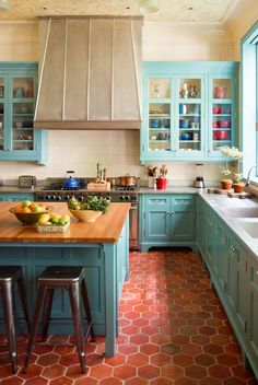 a kitchen with blue cabinets and wooden counter tops, an island in the middle has fruit on it