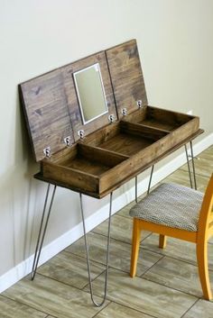 a wooden desk with hairpin legs and a mirror on the top, sitting next to a chair