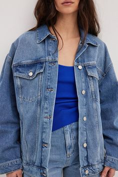 This denim jacket is oversized and made of organic cotton. It has a classic collar, drop shoulders and long sleeves with a button cuff. Our denim jacket features front flap pockets on the chest, open side pockets, an adjustable button detail on the bottom hem and a button closure. Oversized Denim Jacket With Patch Pockets For Everyday, Oversized Denim Jacket With Button Closure For Everyday, Oversized Denim Shacket With Pockets, Oversized Denim Jacket With Buttoned Pockets For Everyday, Oversized Denim Jacket With Lapel Collar For Work, Oversized Cotton Denim Jacket With Patch Pockets, Oversized Medium Wash Long Sleeve Utility Jacket, Oversized Medium Wash Utility Jacket For Spring, Oversized Medium Wash Utility Jacket With Long Sleeves