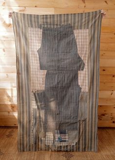 an old piece of clothing is hanging on a wood paneled wall in front of a wooden floor