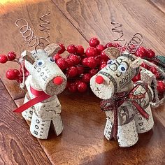 two paper mache reindeers with red berries on the ground next to each other