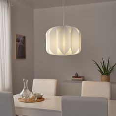 a white dining room table and chairs with a light fixture hanging over it's head