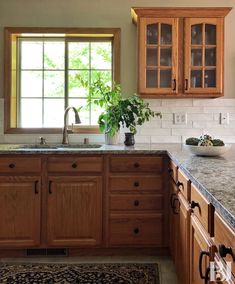 a kitchen with wooden cabinets and granite counter tops, along with a rug on the floor