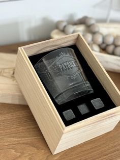 an empty glass bottle sitting in a wooden box on a table next to some beads