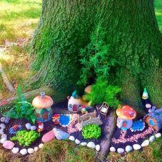 a fairy garden in the shape of a tree trunk with mushrooms and houses on it