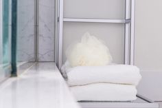 a stack of white towels sitting on top of a metal shelf next to a bath tub