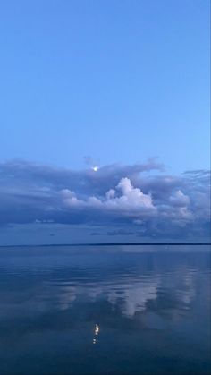 the sky and clouds are reflected in the still water on this calm day at sea