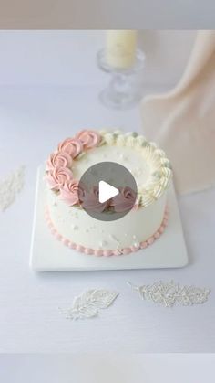 a white cake with pink icing and flowers on it sitting on top of a table