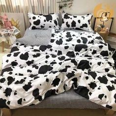 a bed with black and white cow print on it's sheets, pillows and pillow cases