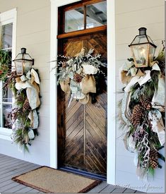 two christmas wreaths hanging on the front door of a house with lights and decorations