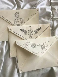 two envelopes with drawings on them sitting on a bed