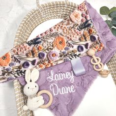 a purple dog bandana with an embroidered bunny on it and a name tag attached to it