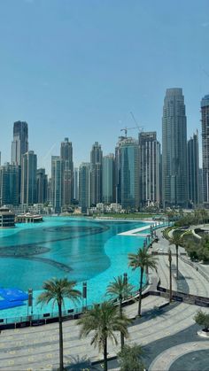 a large body of water surrounded by tall buildings and palm trees in the foreground