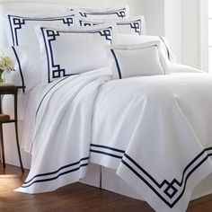 a bed with white sheets and blue trim