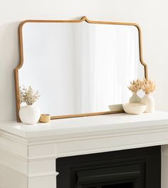 a mirror sitting on top of a white mantle next to a vase and potted plant