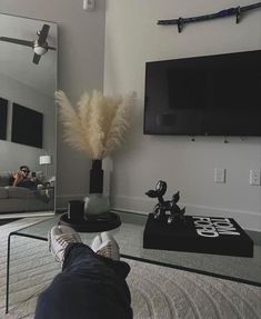 a person's feet resting on a coffee table in front of a large mirror