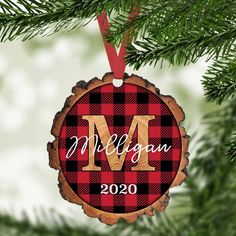 a christmas ornament hanging on a tree branch with the letter m in it