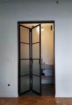 an open door in the middle of a room with hard wood flooring and white walls