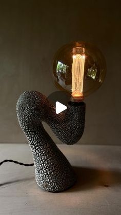 a light that is sitting on top of a table next to a lamp with an object in the shape of a human hand