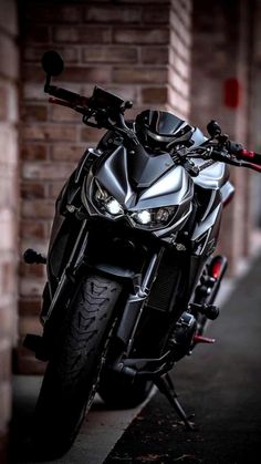 a black motorcycle parked in front of a brick building with lights on it's headlight