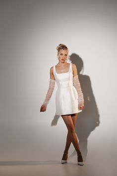 a woman in a short white dress is posing