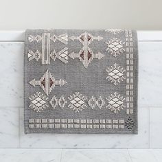 a towel hanging on the wall next to a white tiled bathroom counter with marble flooring