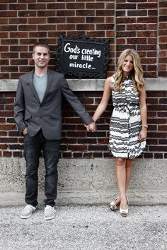 a man and woman holding hands in front of a sign that says god's creation our little miracle