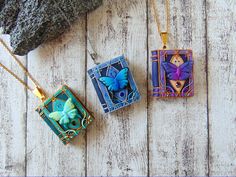 three necklaces with different designs on them sitting on a wooden table next to a rock