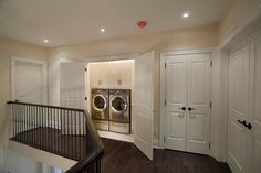 a washer and dryer in a room with wooden floors, white walls and doors