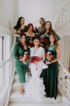 a group of women in green dresses standing on the stairs with flowers and bouquets