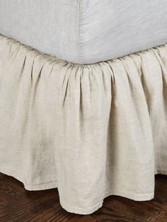 the bed skirt is made from linen and has ruffled edges on it's sides