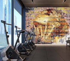 there is a mural on the wall behind some exercise bikes in this gym area with brick walls and floor to ceiling windows