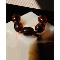 a bracelet made out of glass beads on top of a piece of white marble with brown highlights