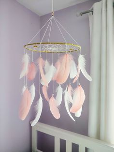 a baby crib with pink and white feathers hanging from it