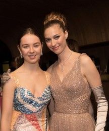 two women standing next to each other at a formal event wearing evening gowns and gloves