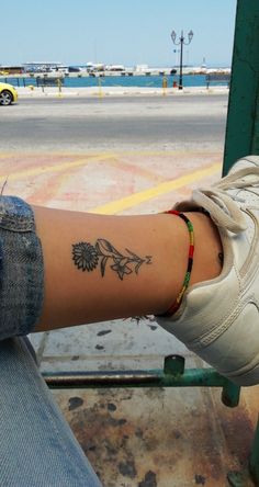 a person with a tattoo on their arm sitting in front of a parking lot next to the ocean