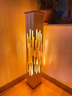 a lamp made out of wooden sticks on a table next to a potted plant