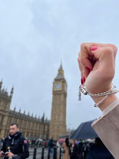 a woman holding up her hand in front of the big ben clock tower