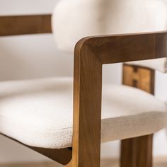 a close up of a wooden chair with a white cushion