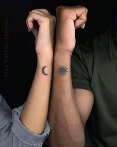 two people with matching tattoos on their arms, one holding the other's arm