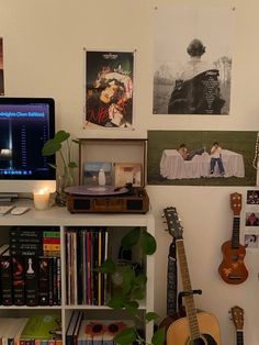 a desk with a computer, guitar and books on it