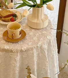 a white table topped with a plate of food and a vase filled with tulips