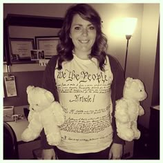 a woman holding two white teddy bears in her hands while standing next to a desk