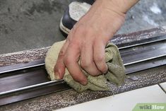 a person wiping down the edge of a metal grate with a microfit cloth