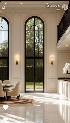 an elegant dining room with white walls and flooring, chandeliers and large windows