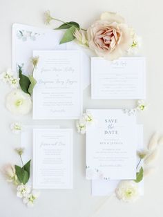 the wedding stationery is laid out on top of each other with flowers and greenery