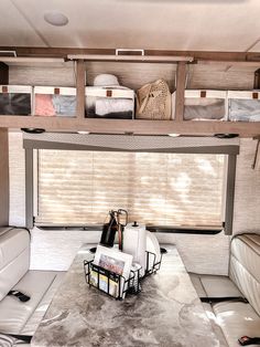 the interior of a recreational vehicle with white leather couches and storage bins on each side