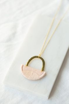 "This series of pendants were inspired by the landscapes we explored with our little ones in the summer. Rolling hills and peaks all to be found in Yorkshire. This small pendant is made from Blush cotton and is fully interfaced to provide support. I have stitched the edges and curved pattern using a matching Blush thread. This is suspended under a hammered brass arc and hangs from an 18\" chain of gold vermeil (sterling silver plated with 18ct gold). I have enamelled the brass arc to prevent tar Handmade White Necklace For Everyday, Handmade White Necklace For Everyday Use, Pink Handmade Minimalist Necklaces, Handmade Minimalist Pink Necklaces, Pink Handmade Minimalist Necklace, Handmade Pink Everyday Necklaces, Minimalist Handmade Pink Necklace, Handmade Minimalist Pink Necklace, Handmade Pink Necklaces For Everyday Wear